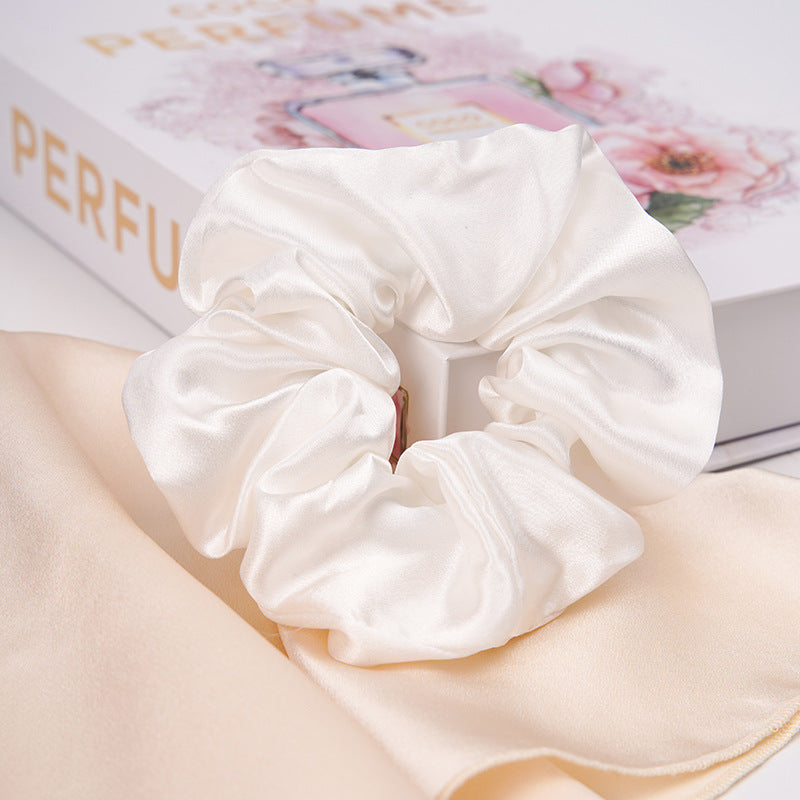 A pastel - pink 100% silk scrunchie worn on a woman's wrist and in her hair-17