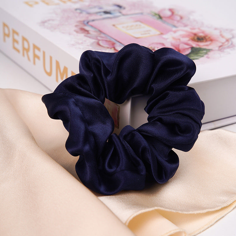 A pastel - pink 100% silk scrunchie worn on a woman's wrist and in her hair-18