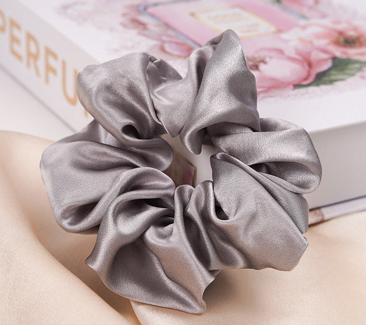 A pastel - pink 100% silk scrunchie worn on a woman's wrist and in her hair-2