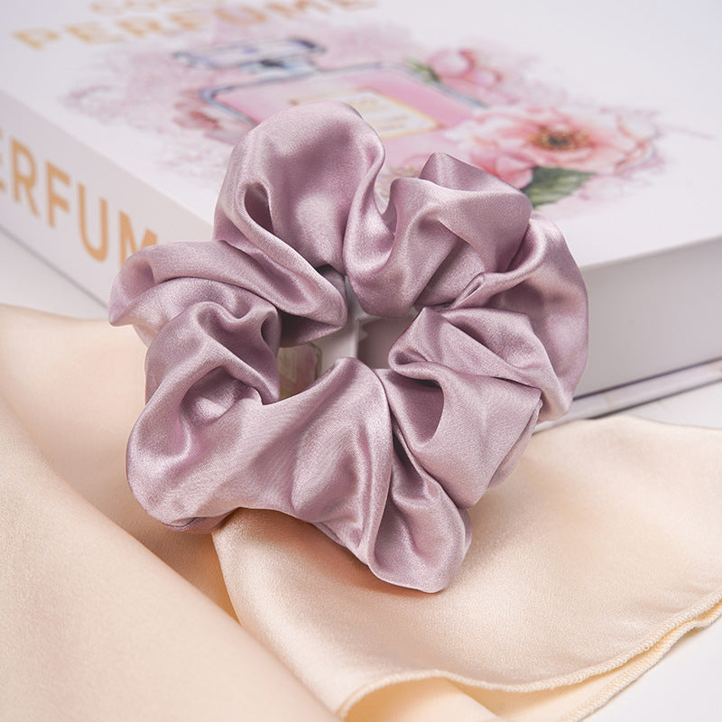 A pastel - pink 100% silk scrunchie worn on a woman's wrist and in her hair-13