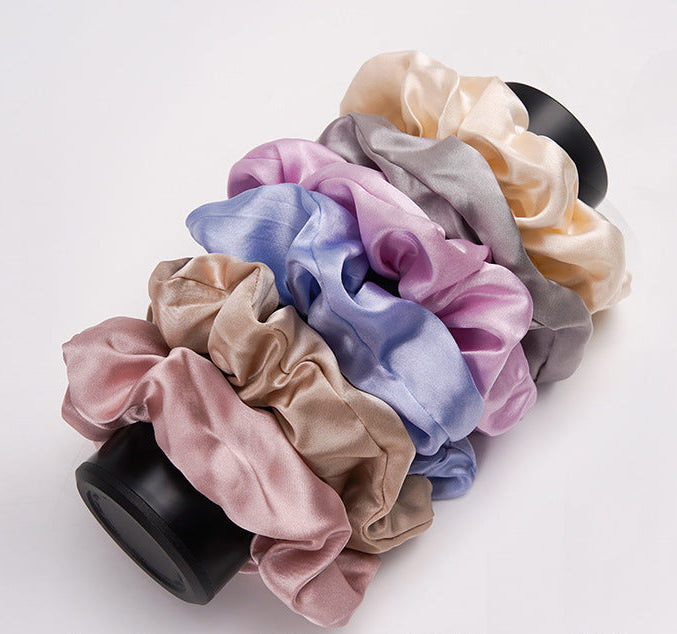 A pastel - pink 100% silk scrunchie worn on a woman's wrist and in her hair-4