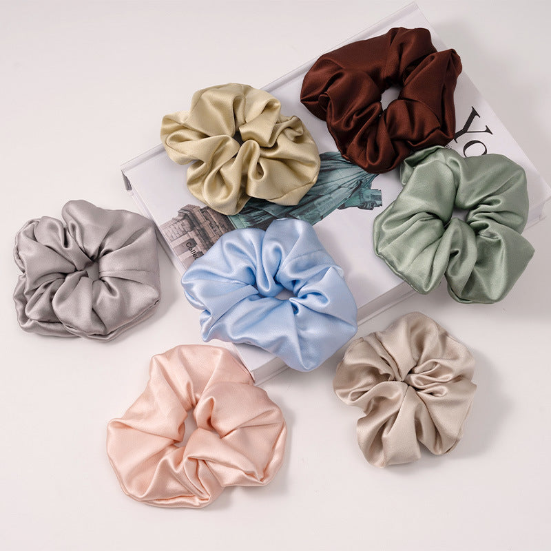 A set of silk scrunchies in various colors including beige, blue, brown, and more