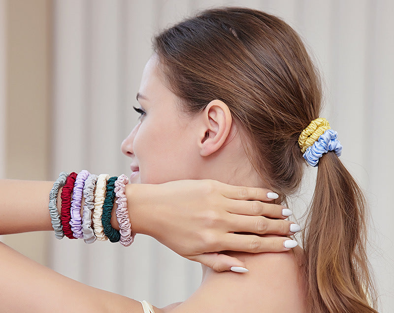 A woman wearing colorful 100% silk scrunchies in her hair and on her wrist