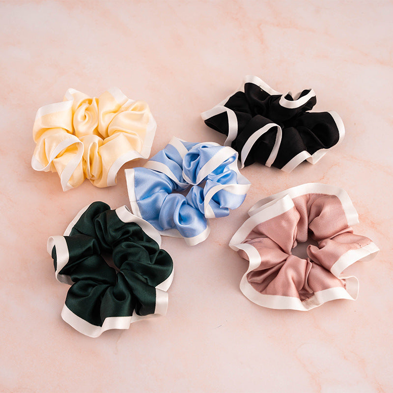 A set of colorful 100% silk scrunchies in beige, black, blue, green, and pink