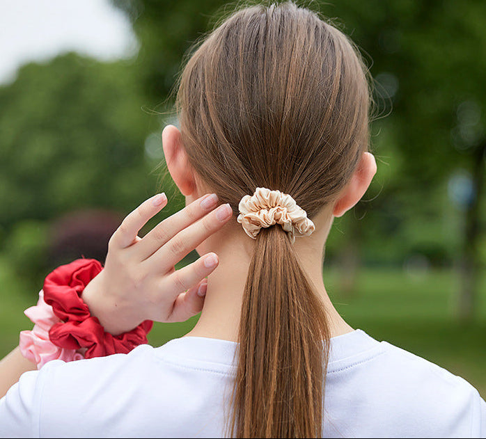 A light - colored 100% silk scrunchie in a woman's hair-2