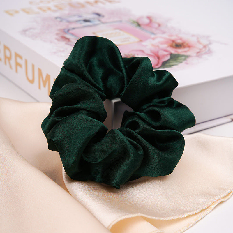A pastel - pink 100% silk scrunchie worn on a woman's wrist and in her hair-8