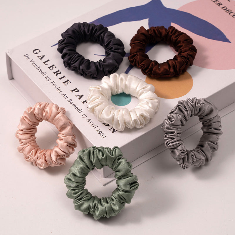 A set of silk scrunchies in black, brown, white, pink, green, and gray colors