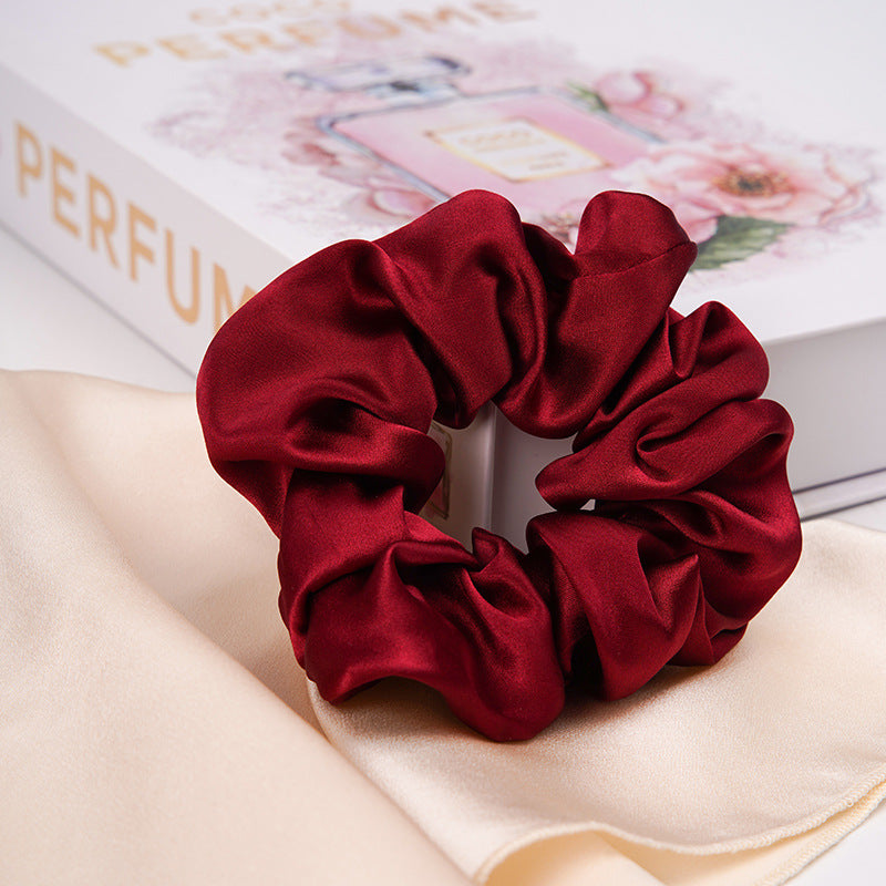 A pastel - pink 100% silk scrunchie worn on a woman's wrist and in her hair-10