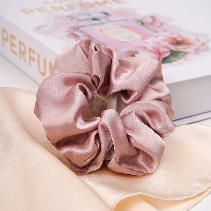 A pastel - pink 100% silk scrunchie worn on a woman's wrist and in her hair-6