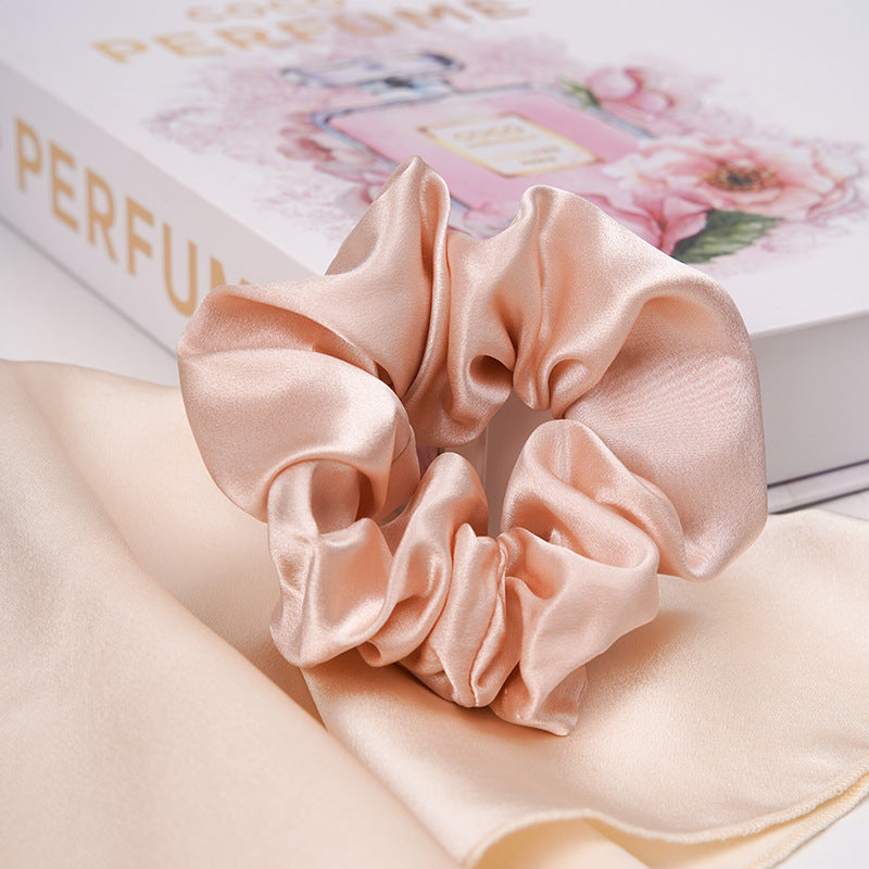 A pastel - pink 100% silk scrunchie worn on a woman's wrist and in her hair-7