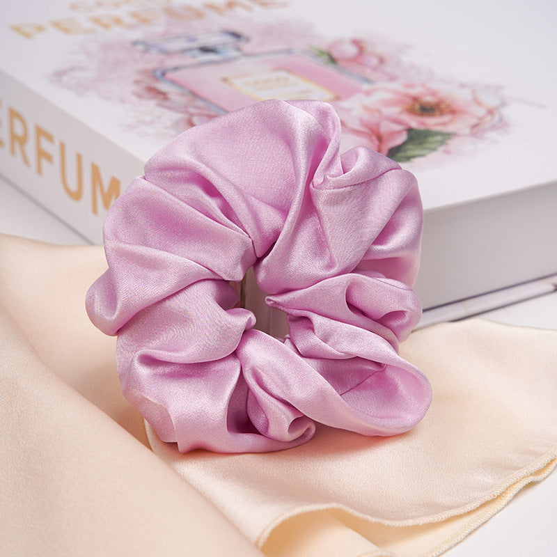 A pastel - pink 100% silk scrunchie worn on a woman's wrist and in her hair-16