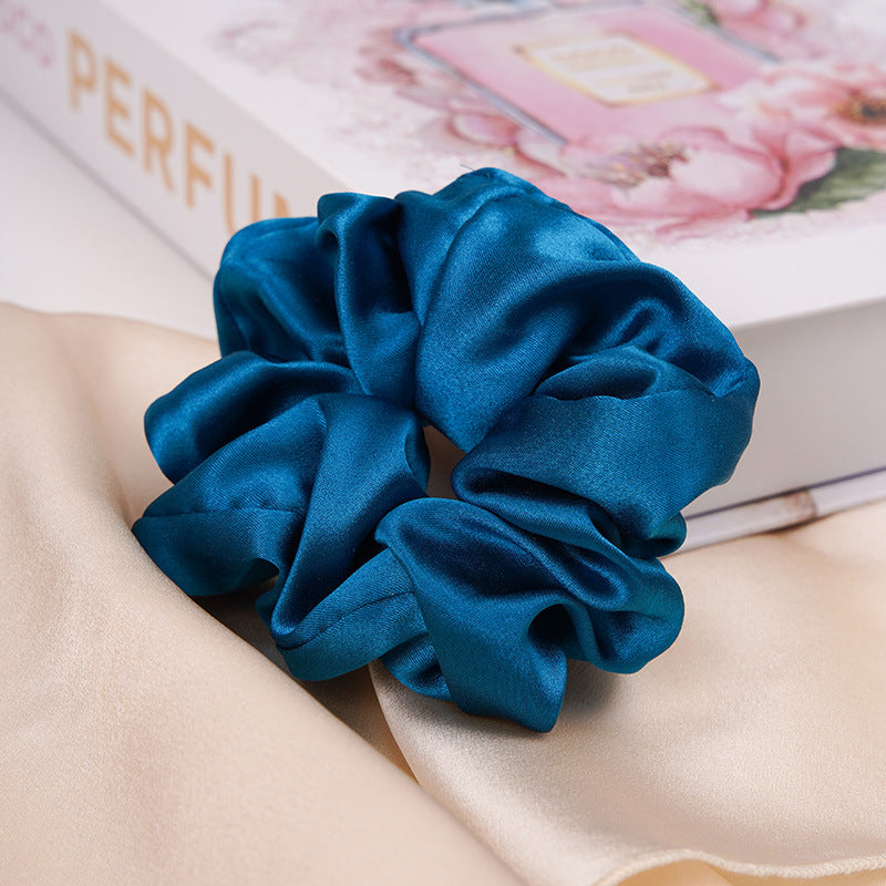 A pastel - pink 100% silk scrunchie worn on a woman's wrist and in her hair-12
