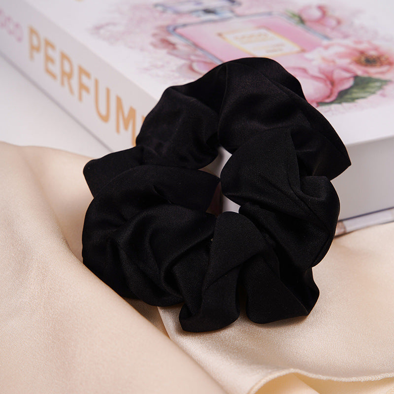 A pastel - pink 100% silk scrunchie worn on a woman's wrist and in her hair-9