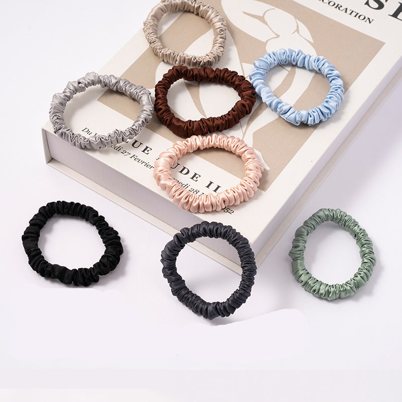 A set of silk scrunchies in black, gray, beige, brown, light blue, pink, and green colors
