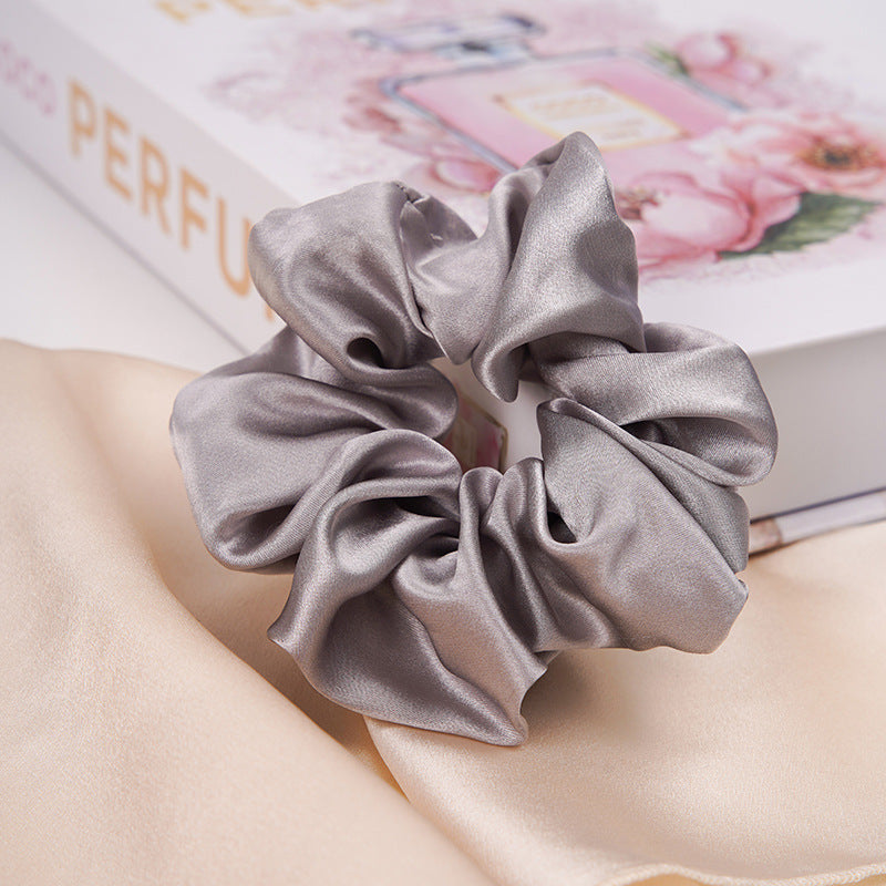 A pastel - pink 100% silk scrunchie worn on a woman's wrist and in her hair-14
