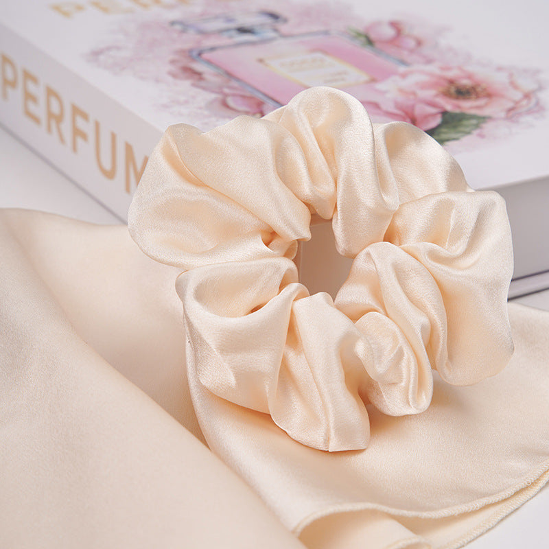 A pastel - pink 100% silk scrunchie worn on a woman's wrist and in her hair-21